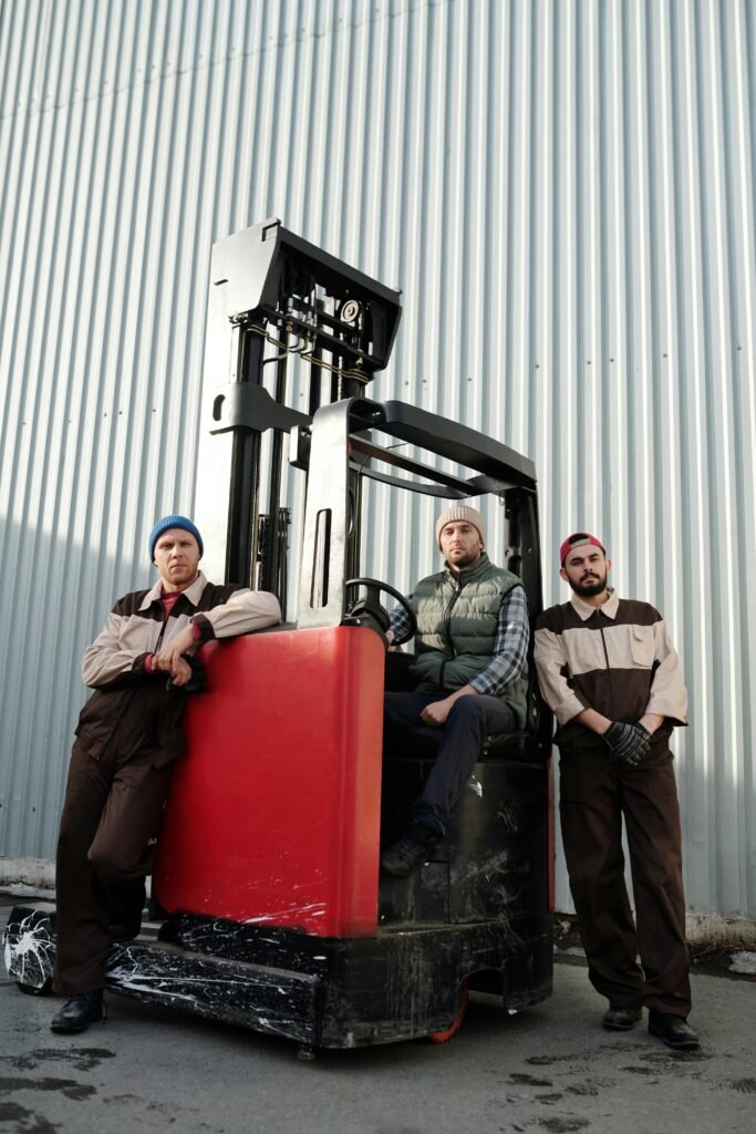 Three workers with a forklift at an industrial location, exemplifying teamwork and heavy equipment operation.