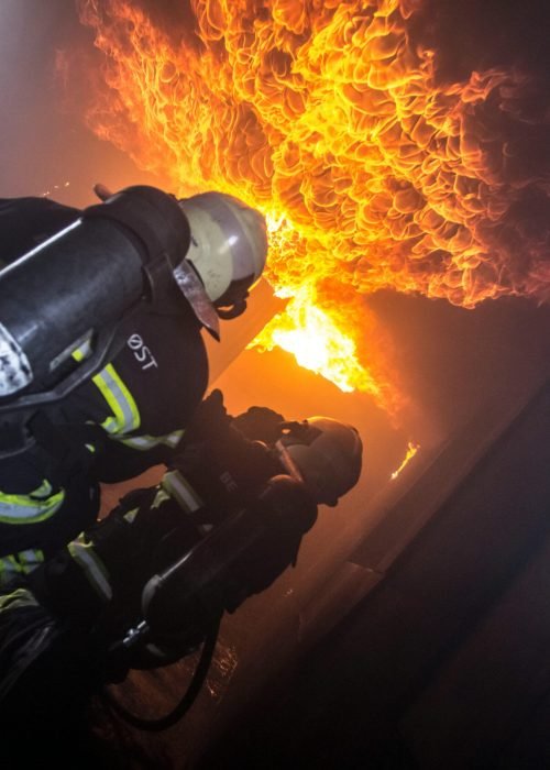 Firefighters courageously fighting a blazing fire indoors, showcasing bravery and teamwork.
